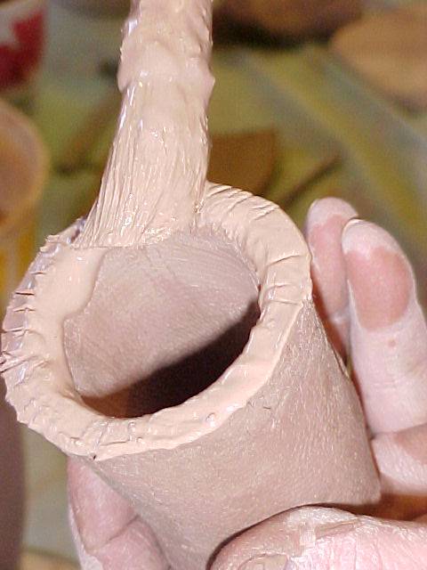 Applying slip to the spout to attach to jug